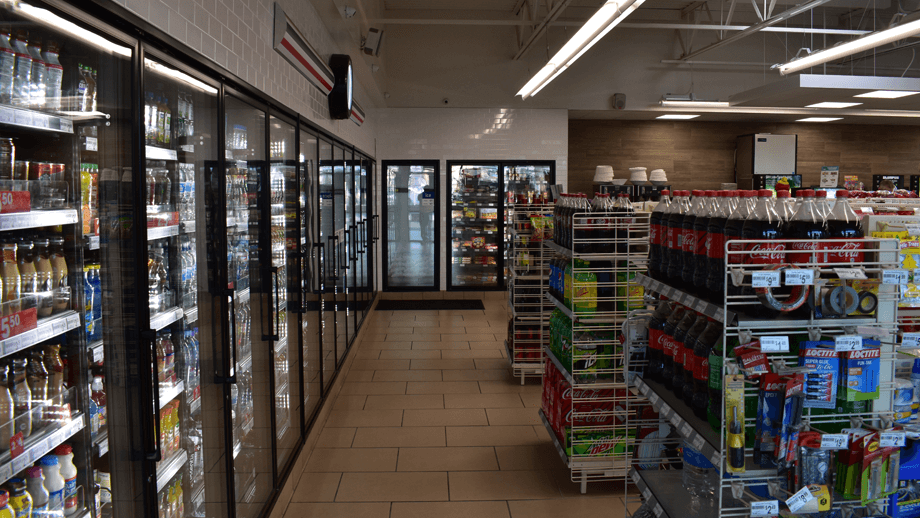 Indoor image of 7-11 showing the deli display fridge and soda machines.