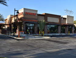 Outdoor image of Dunkin Donuts showing the builidng facade and parking lot.