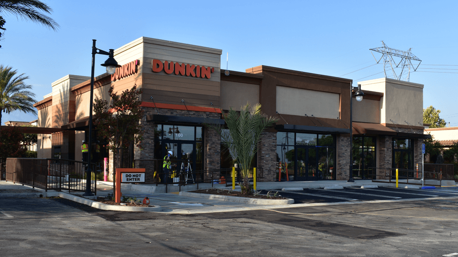 Outdoor image of Dunkin Donuts showing the builidng facade and parking lot.