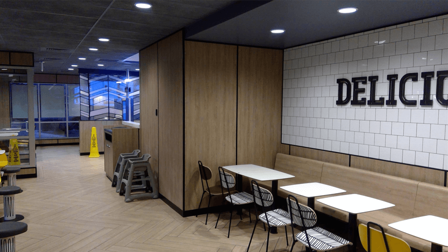 Indoor image of McDonalds showing the dining area with wooden benches and black chairs.