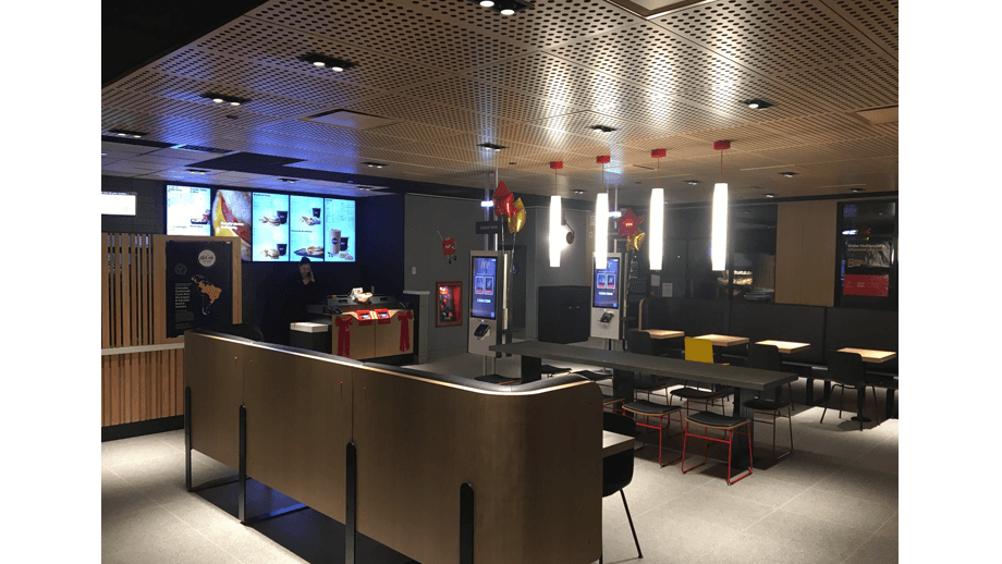 Indoor image of McDonalds showing fabric booths and tall ceiling lamps.